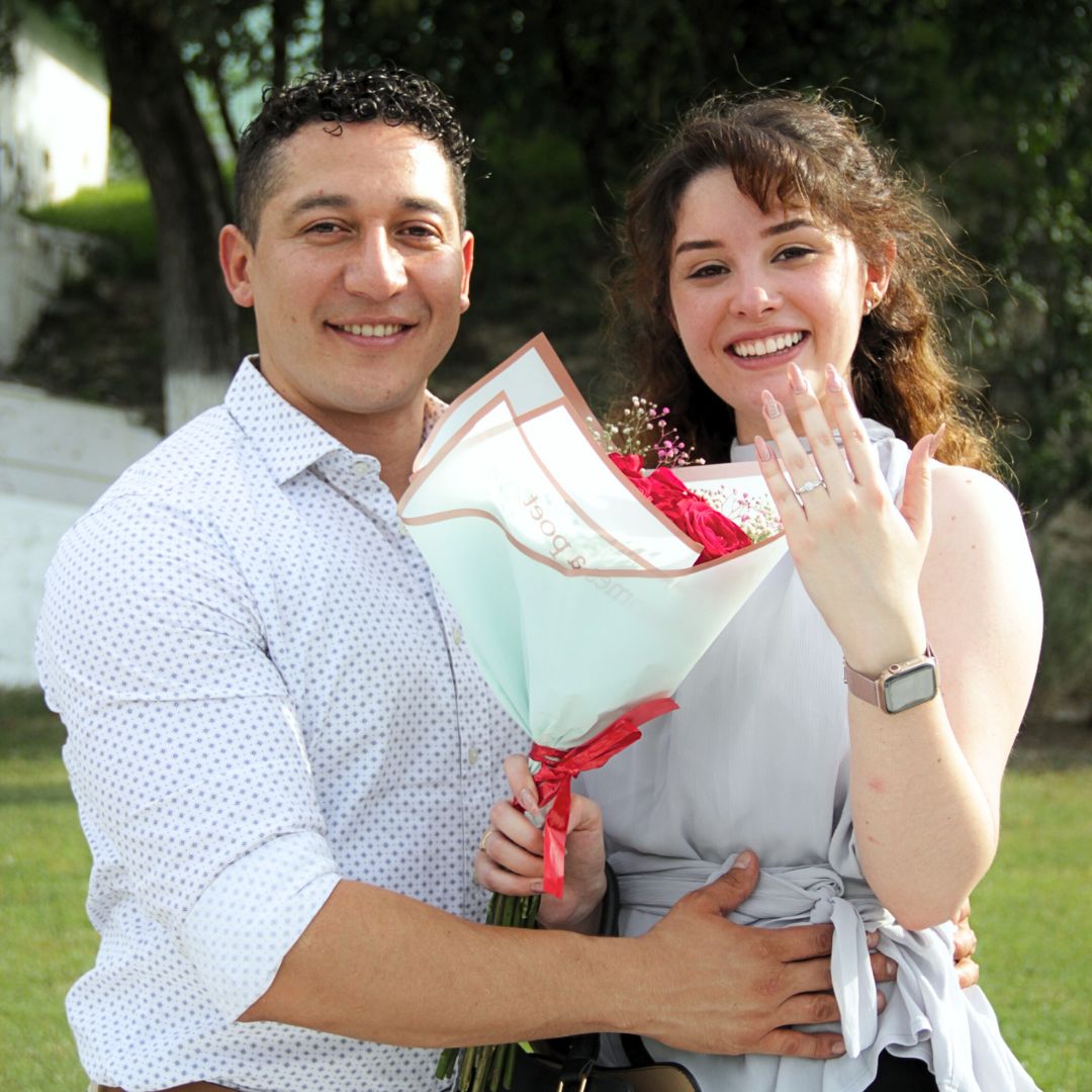 Pareja sonriente después de una propuesta de matrimonio, mostrando el anillo de compromiso tras un paseo en helicóptero en Monterrey.