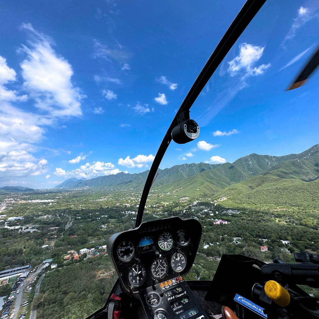 Vista aérea desde la cabina de un helicóptero sobrevolando las montañas de Monterrey con Helicópteros VIP.