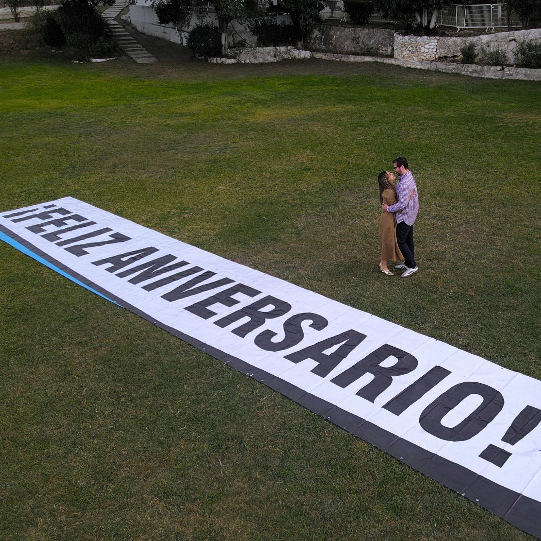 Pareja celebrando su aniversario con mensaje gigante de “Feliz Aniversario” tras un paseo en helicóptero en Monterrey.